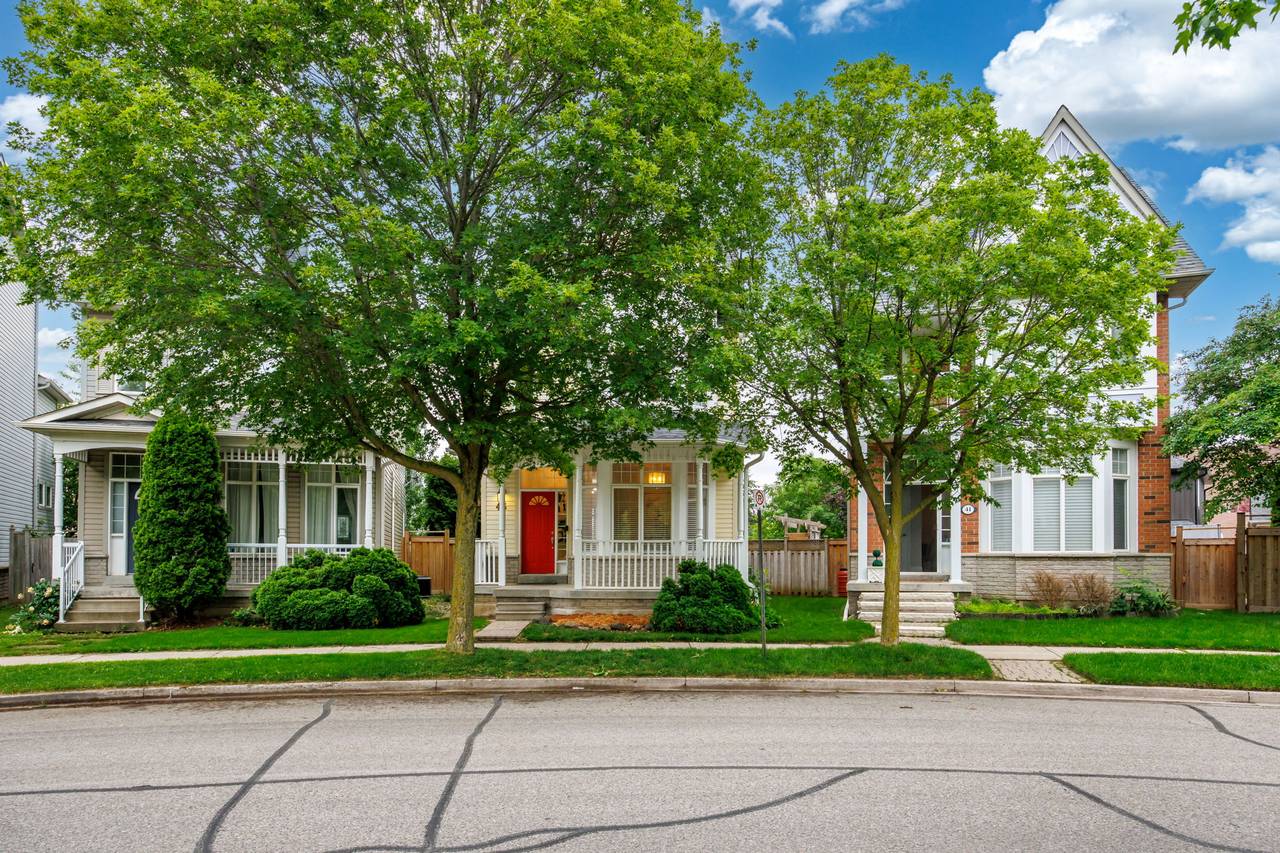 43 Cornell Common Road seen from the street, a two-storey home with a covered front porch and red door, framed by mature trees.